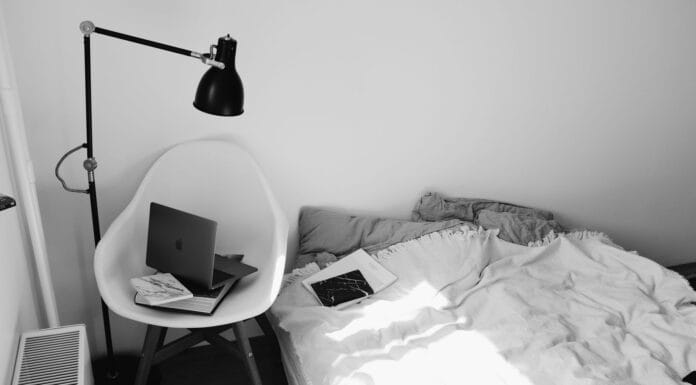 Laptop na krześle w małej, słonecznej sypialni