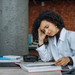 Zmęczona bizneswoman przy biurku z dokumentami finansowymi