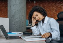 Zmęczona bizneswoman przy biurku z dokumentami finansowymi